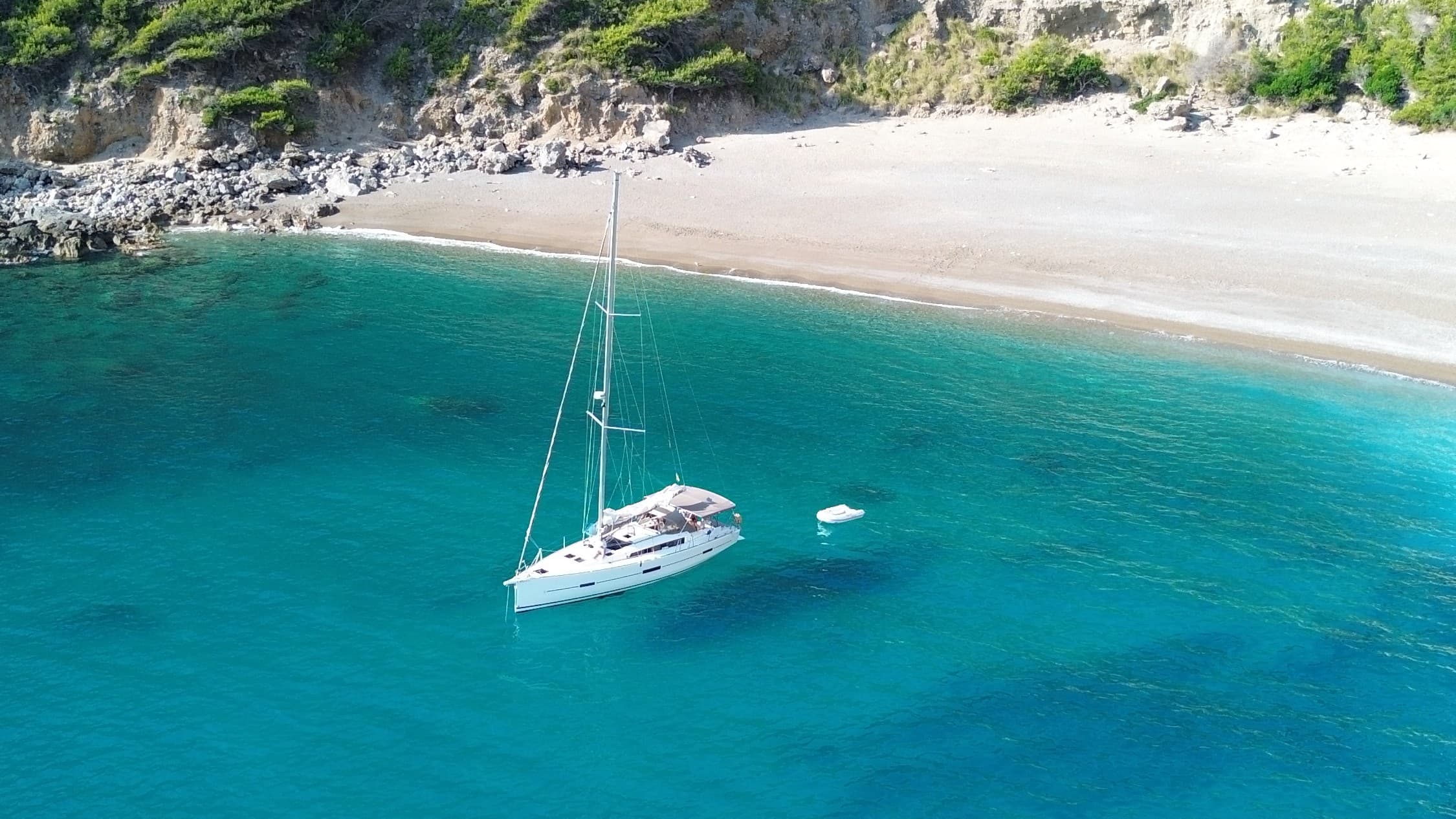 Vista aérea de velero en cala mediterránea